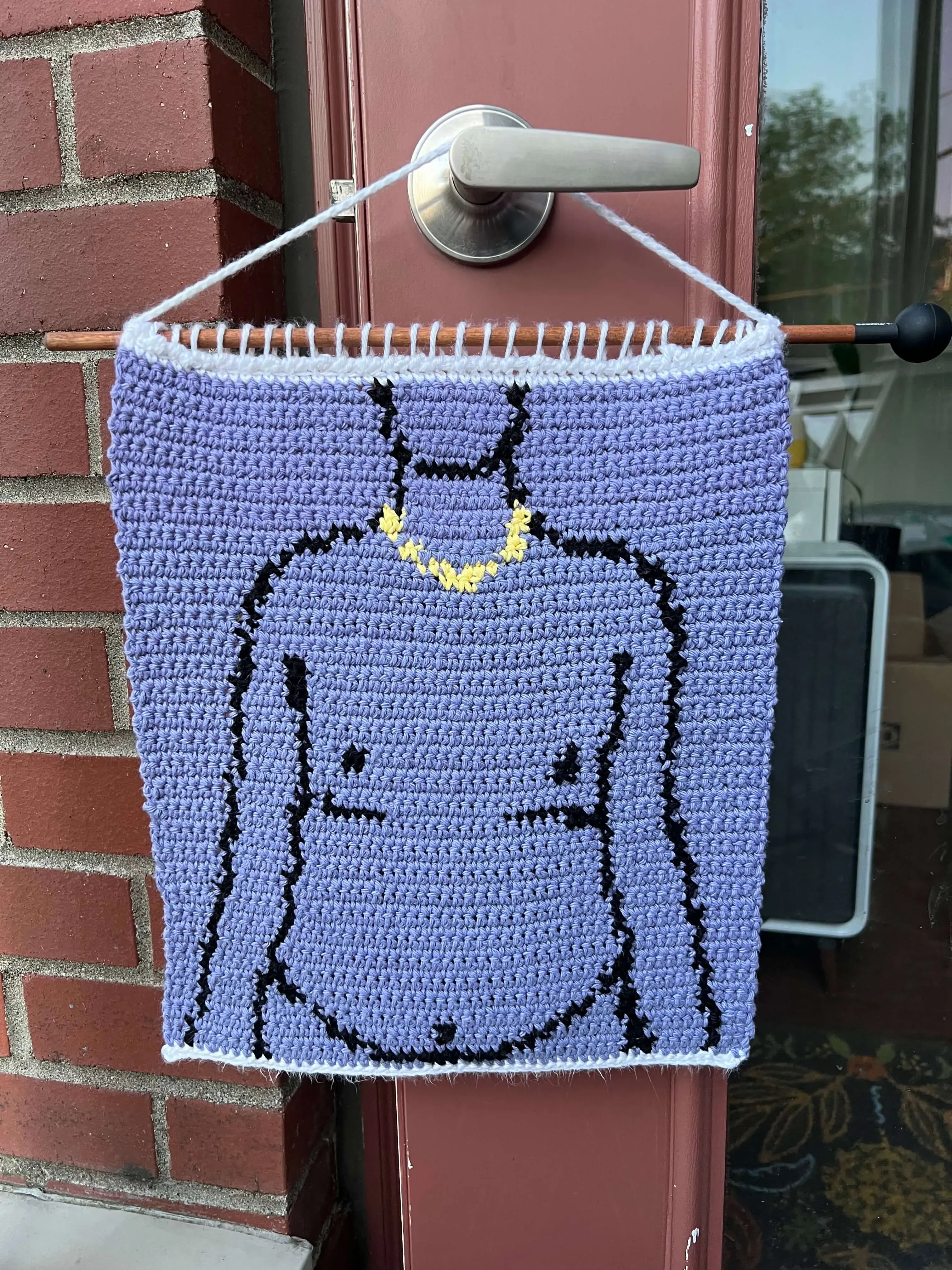 Desire: a crochet tapestry with a purple background and a line drawing of a person wearing a small gold chain with top surgery scars