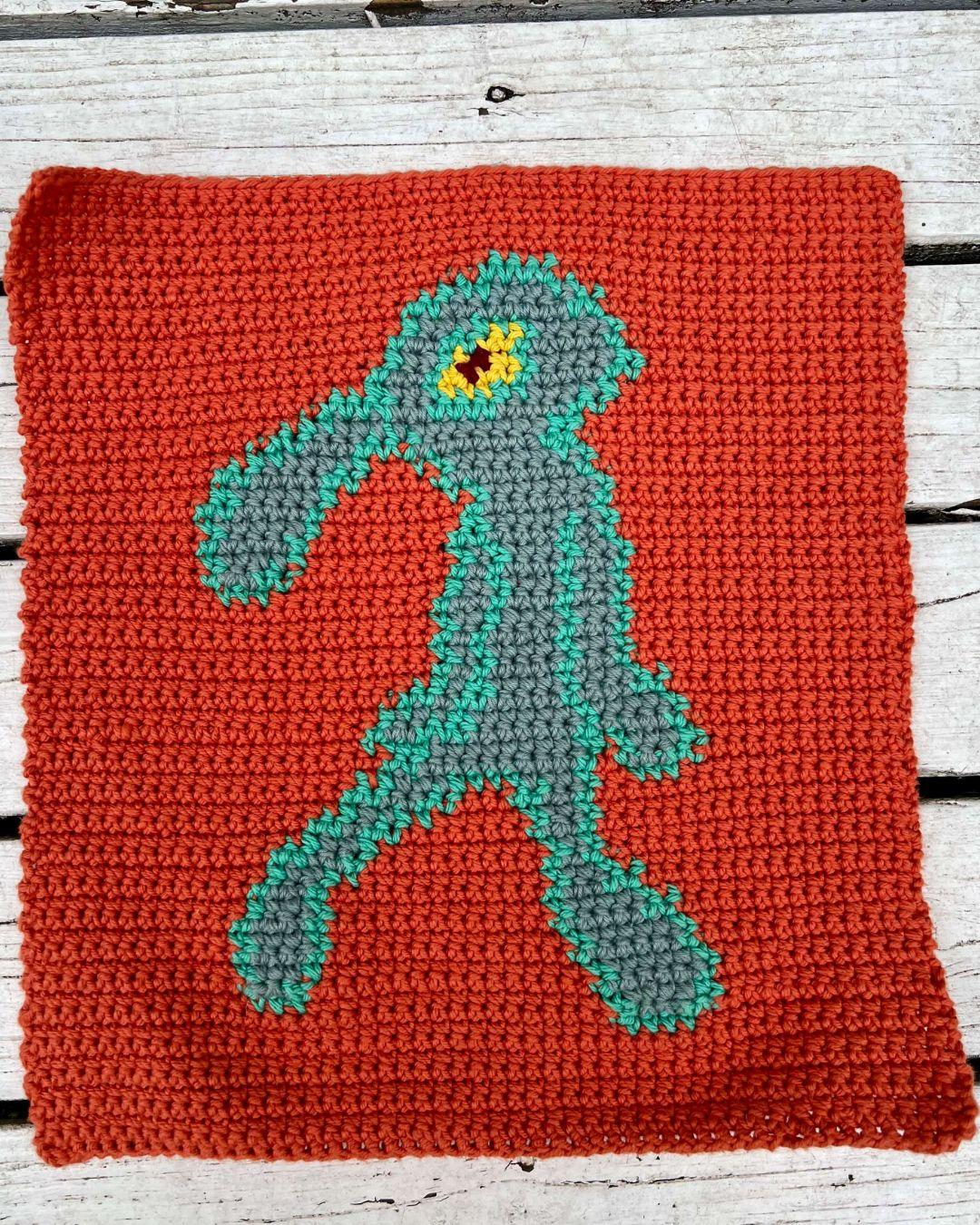 a crochet tapestry with a vibrant orange background and a groovy blue squid